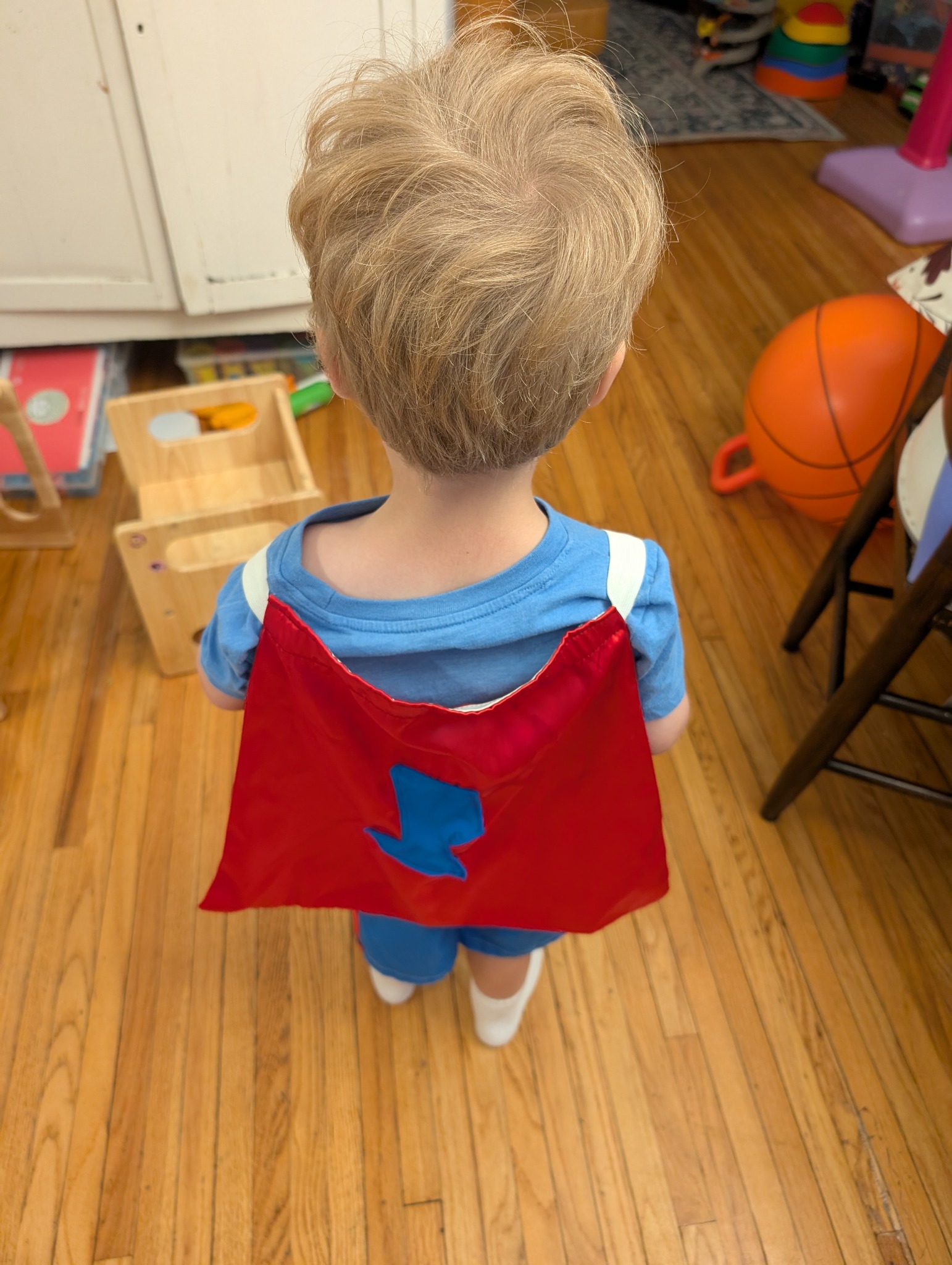 Back view of cape on child under-arm elastic — no neck tie